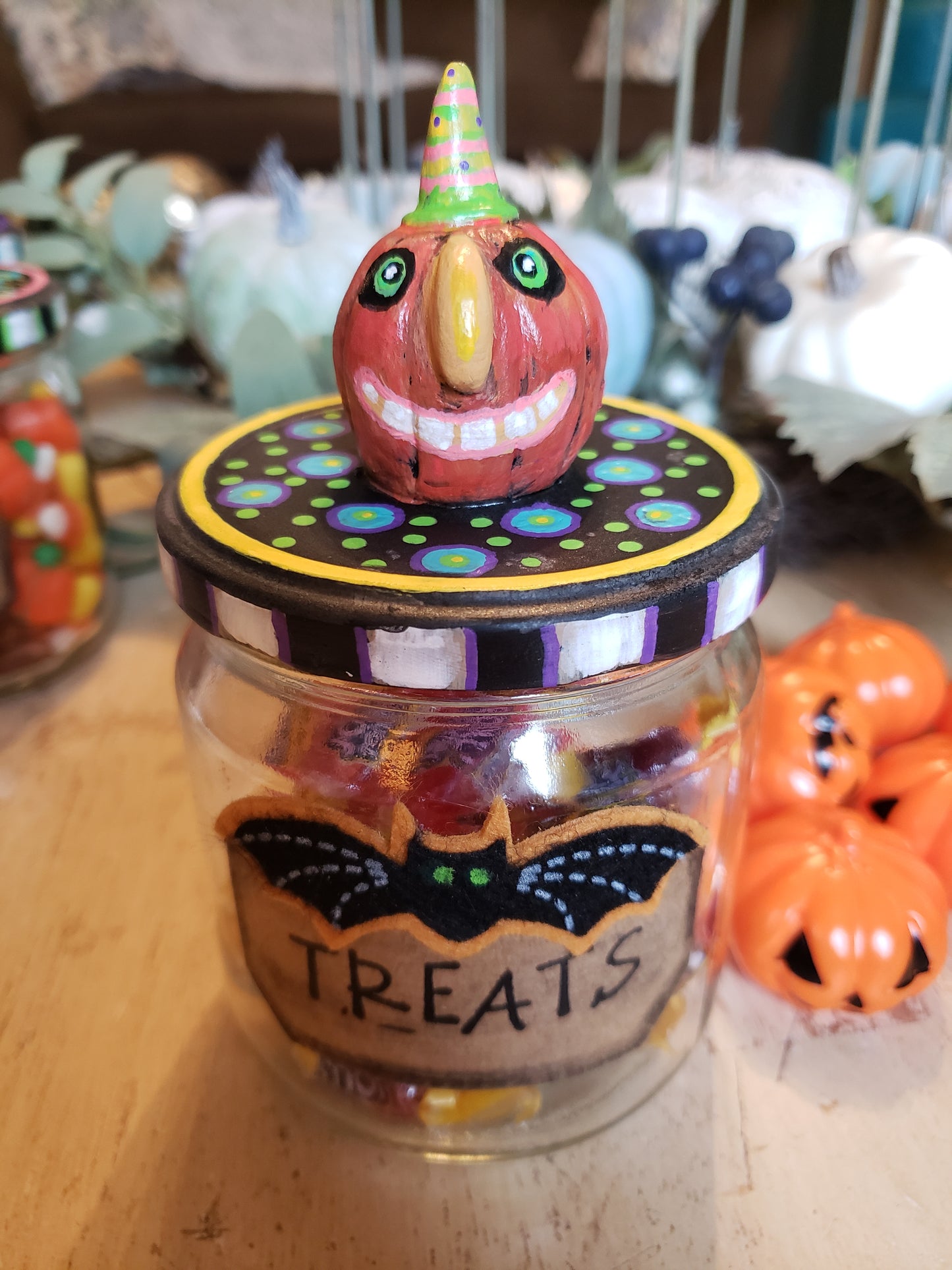 Decorative jar labeled 'Treats' with a colorful monster design on a wooden surface.