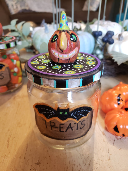Decorative Halloween jar with a small figurine on top, surrounded by festive decorations.