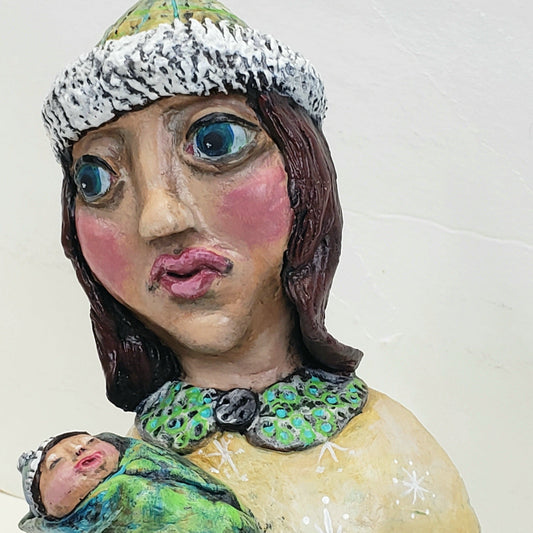 Figurine of a woman holding a baby with text 'Baby It's Cold Outside' hand made from paper clay