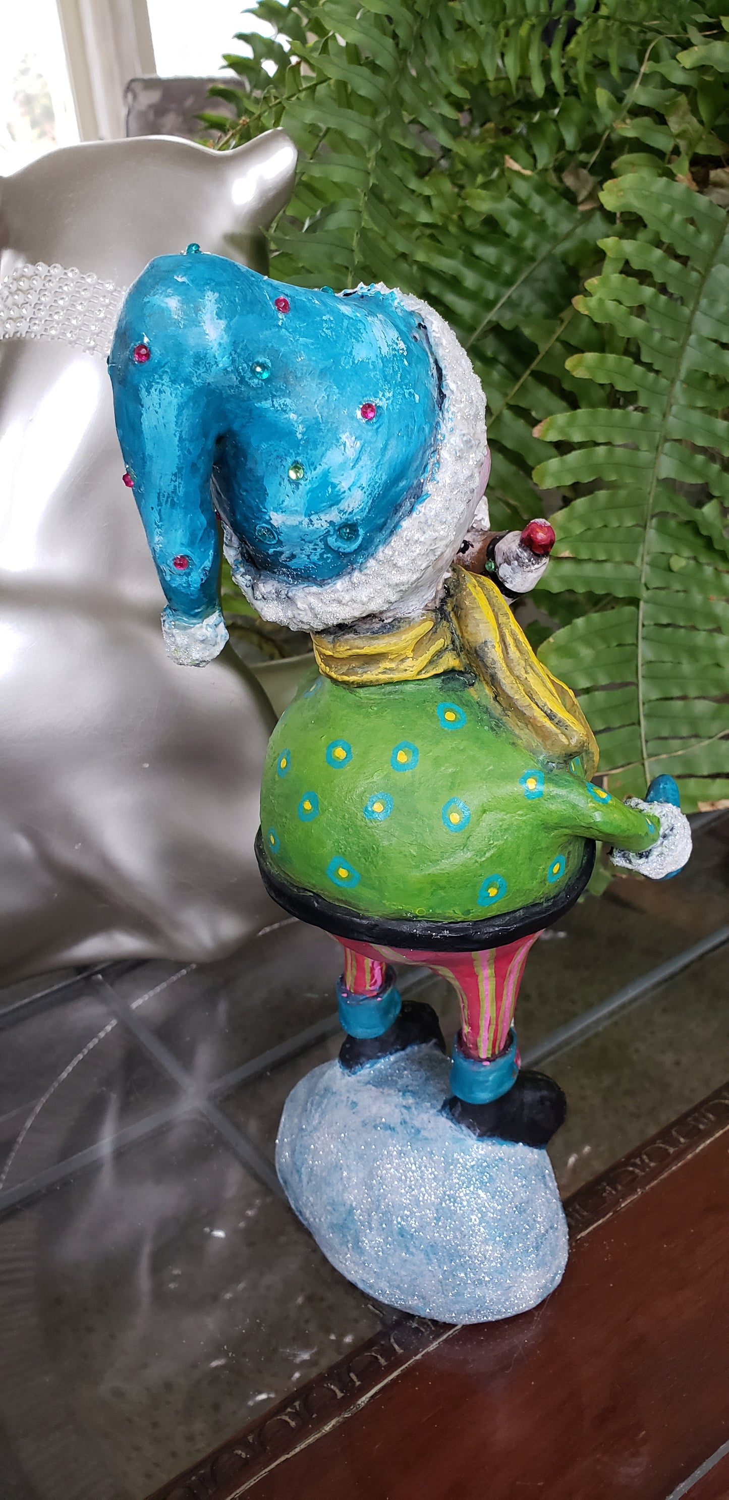 Colorful snowman figurine with blue shoes and green body holding a pogo deer