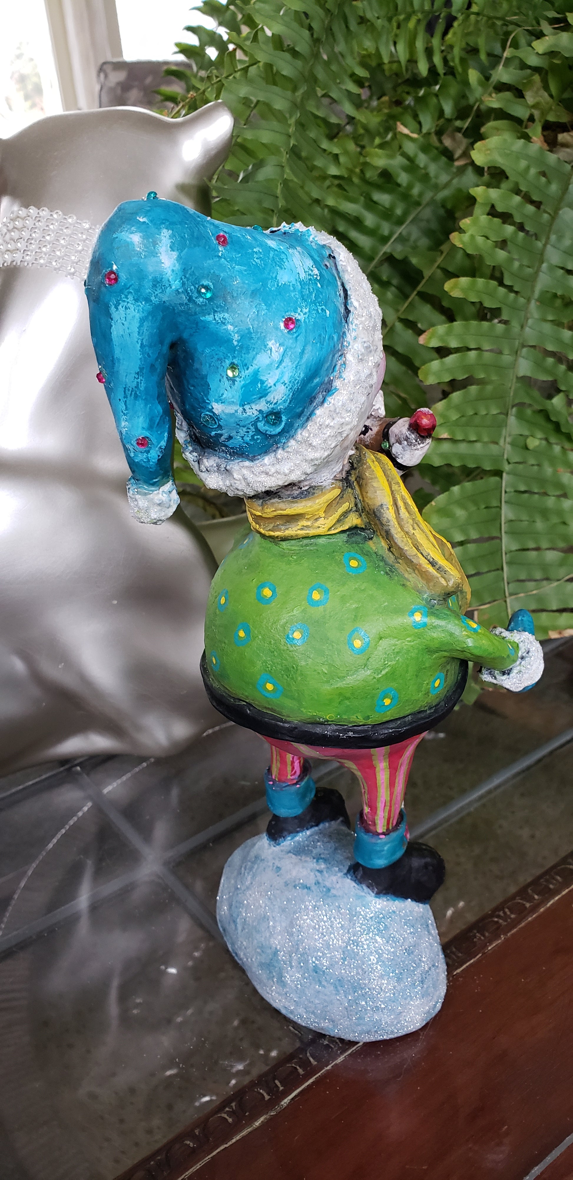 Colorful snowman figurine with blue shoes and green body holding a pogo deer