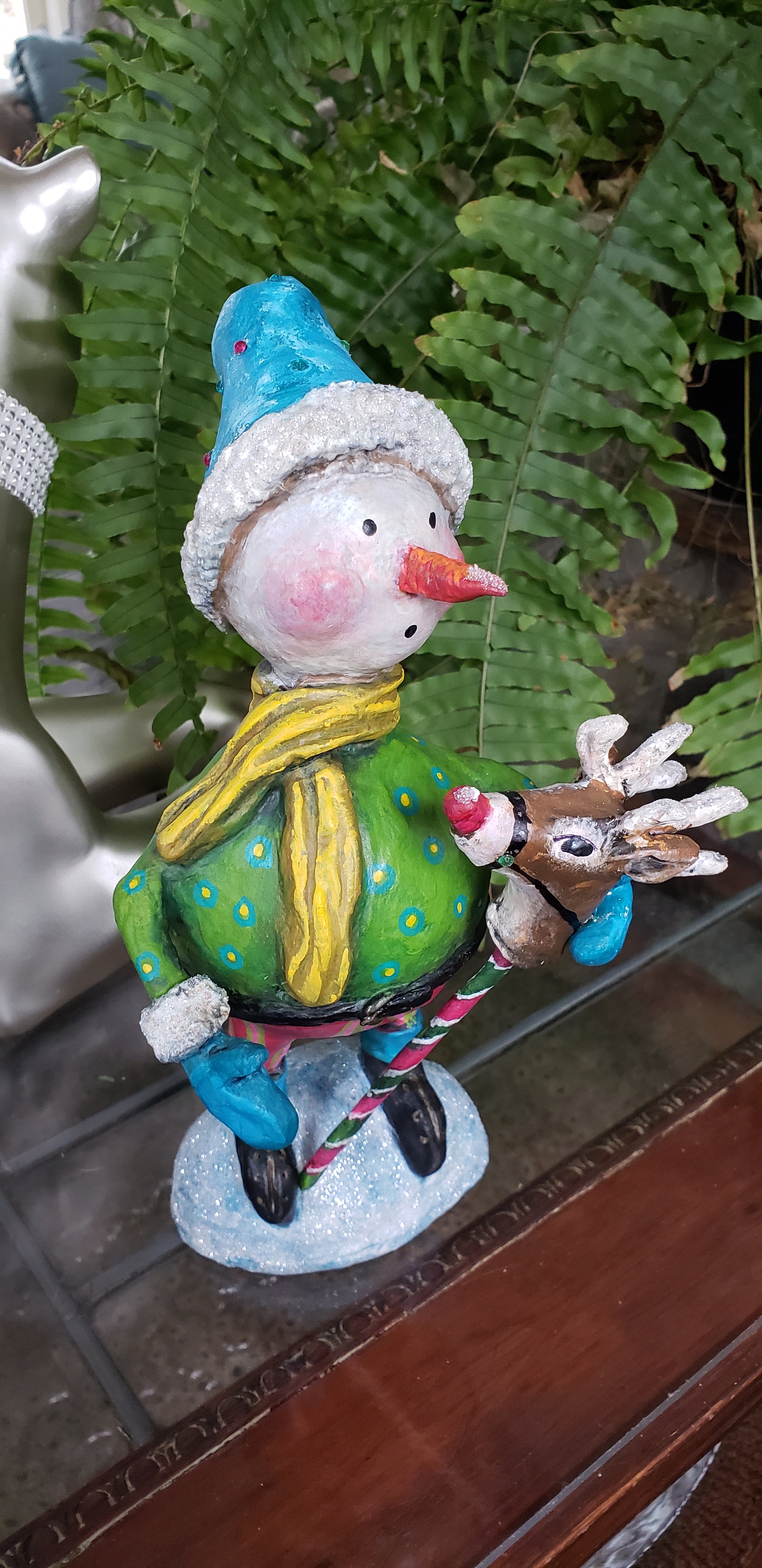 Decorative paper clay figurine of a snowman with a  pogo reindeer on its hand