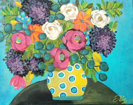 Colorful floral arrangement in a polka dot vase on a solid background