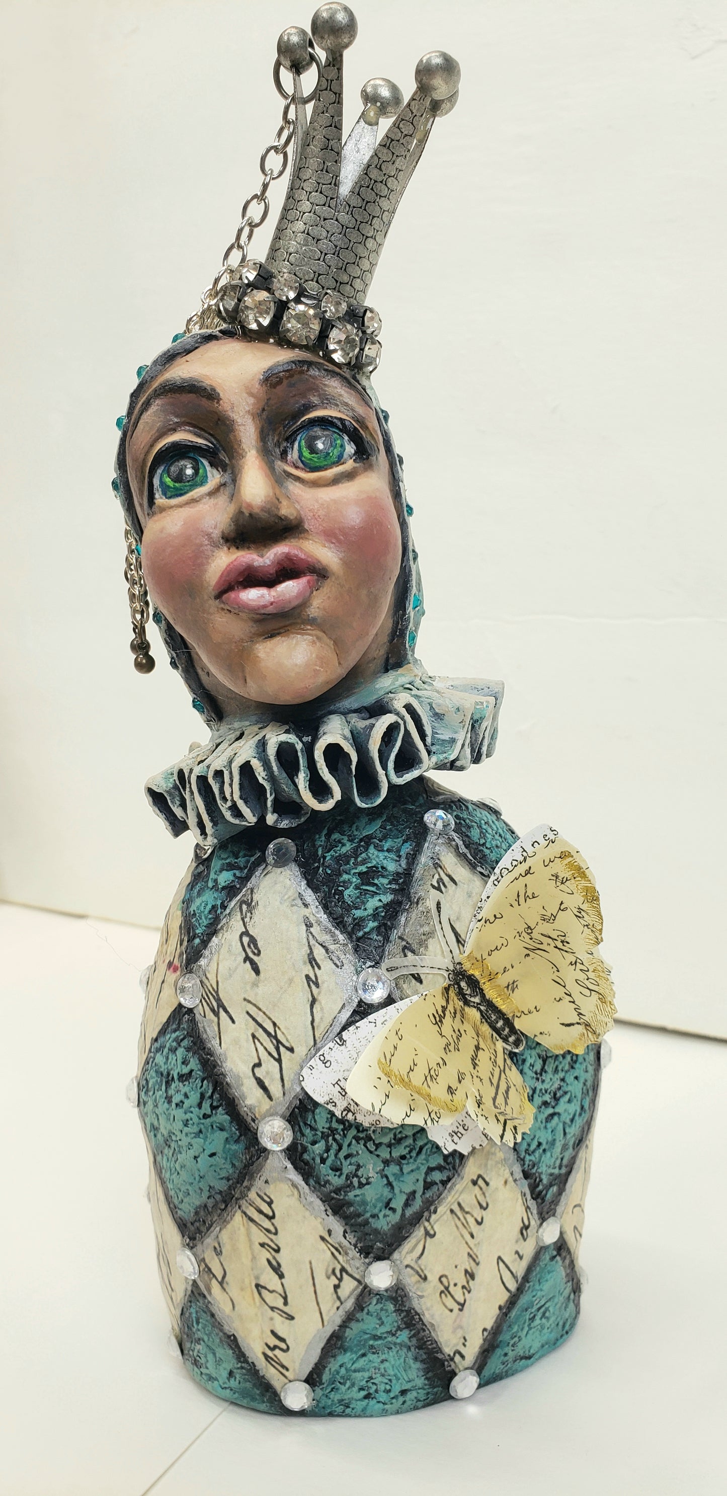 Decorative jesture figurine with intricate design and metal crown and rhinestones teal and antique white with a paper butterfly