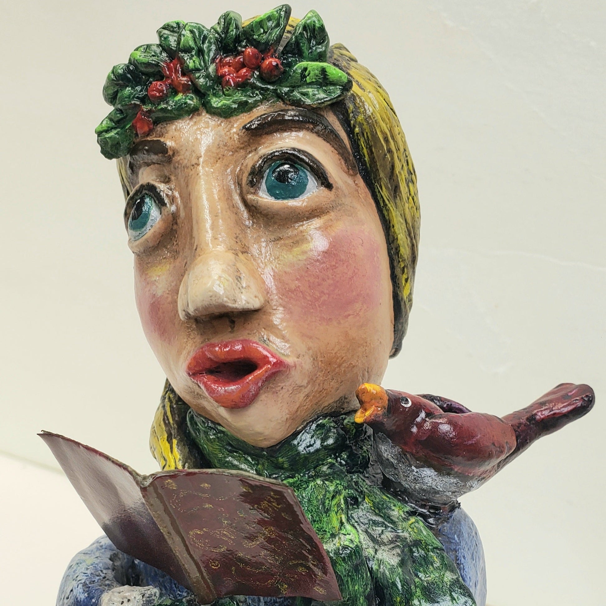 Ceramic figurine of a person with a bird on their shoulder, holding a book titled 'O Holy Night'.