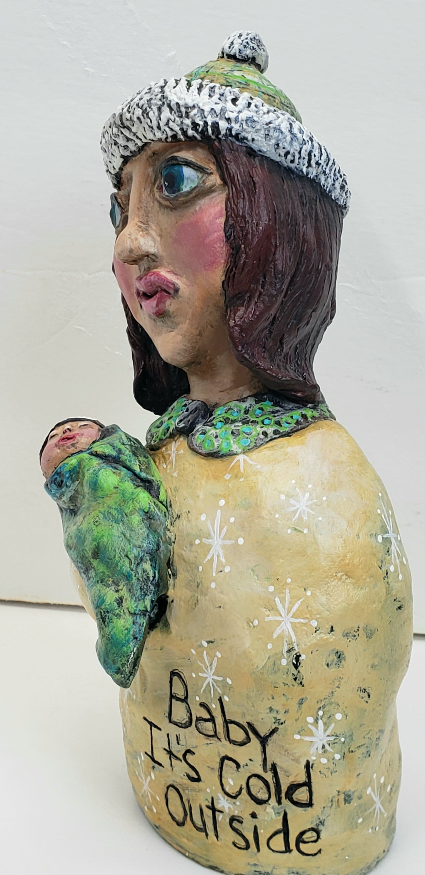 Decorative paper clay figurine of a woman holding a baby with text 'Baby It's Cold Outside' standing Christmas decoration