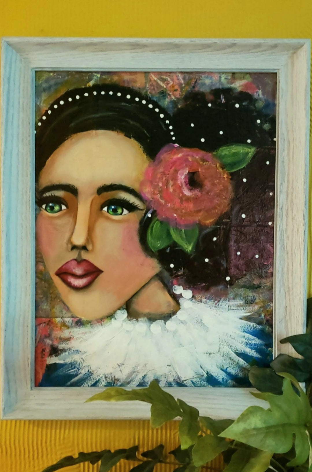 Framed artwork of a stylized portrait with a flower in hair against an abstract background